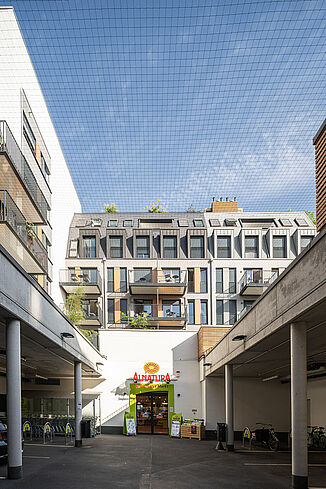 Une entrée avec des places de parking du marché Alnatura se trouve dans la cour intérieure du quartier résidentiel.