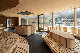 Univers moderne du sauna avec grande façade vitrée et vue sur les montagnes dans les thermes Silvretta à Ischgl.