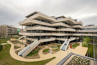 Une partie du bâtiment du Campus Aaron Mencer à Vienne avec des terrasses et des jardins tout autour.