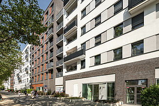 Vue de la rue avec l'entrée du parking souterrain et l'entrée des zones d'habitation dans le quartier à usage mixte Alea à Francfort.