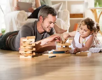Un homme joue avec un enfant sur un plancher en bois.