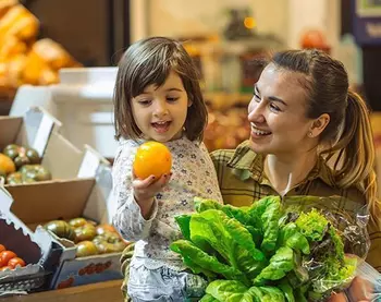 Une femme et un enfant achètent des fruits et des légumes au supermarché.