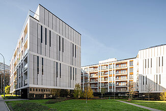 Immeuble d'habitation Piano House à Varsovie avec une cour intérieure verdoyante et des bancs.