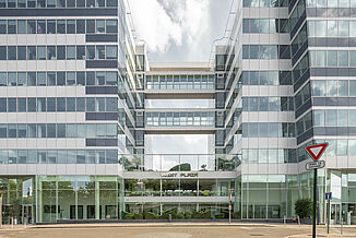 Entrée du bâtiment à usage mixte West Plaza avec façade en verre.