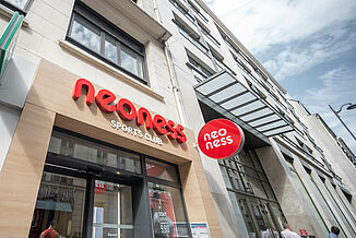 Façade d'un immeuble résidentiel et commercial à Paris, avec une salle de sport neoness au rez-de-chaussée et des appartements au-dessus.