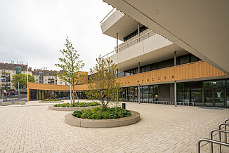 Entrée principale du campus Aaron Mencer à Vienne avec une façade en bois, béton et verre et des terrasses tout autour. sur plusieurs étages.