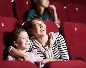 Une femme est assise avec un enfant dans un cinéma.