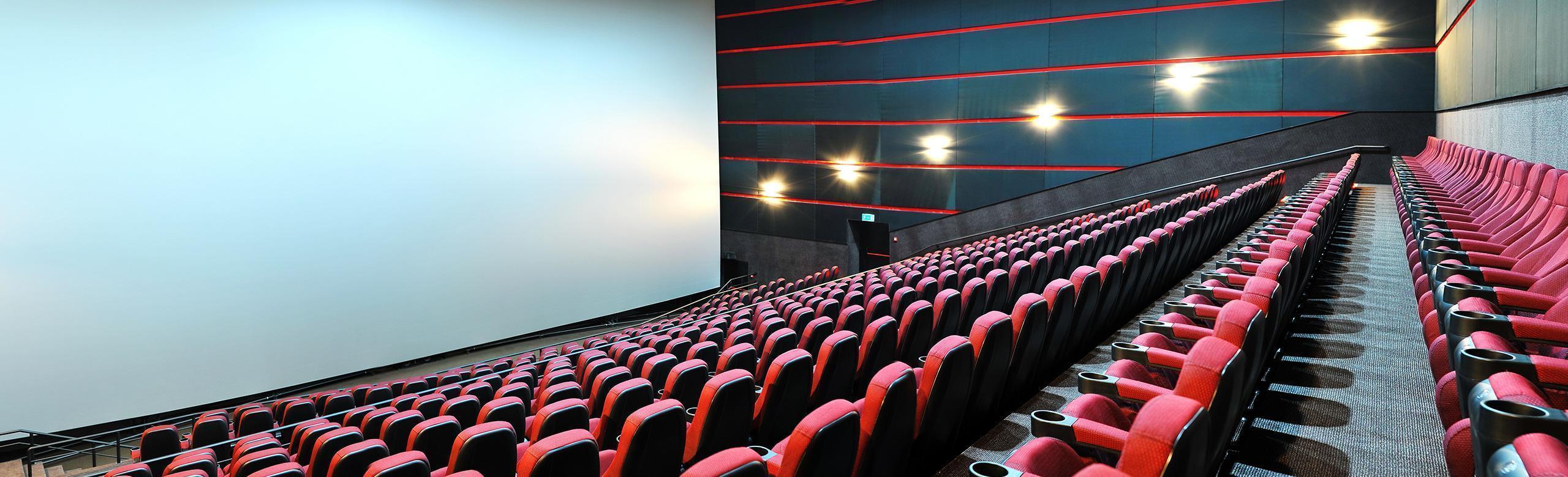 Une grande salle de cinéma avec des fauteuils rouges et un grand écran.