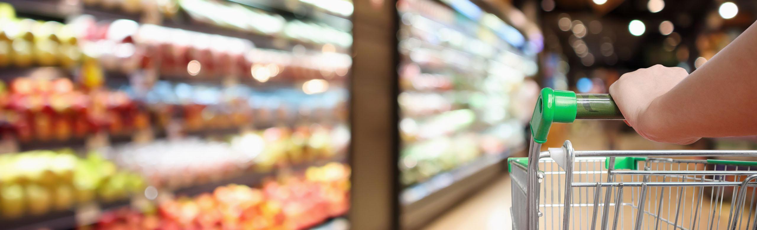 A shopping trolley is pushed through a supermarket and makes rolling noises.